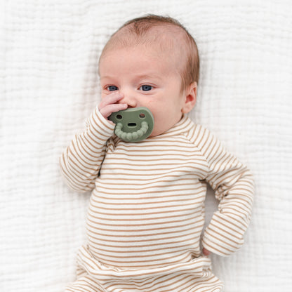 Baby sucking on a Cutie PAT Smile pacifier.