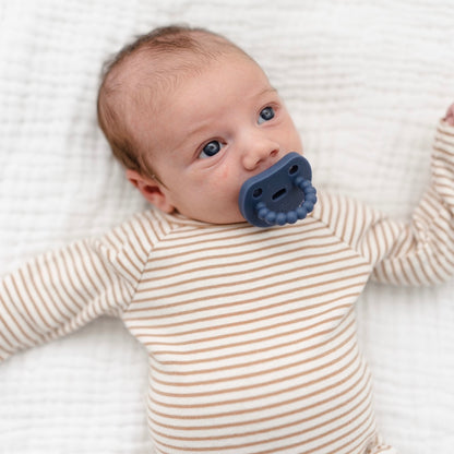 Baby sucking on a Cutie PAT Smile pacifier.