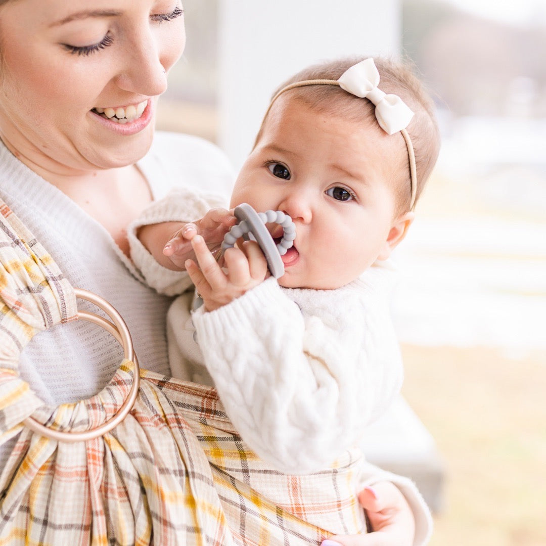 Mom holding baby wearing a Cutie Clip attached to the Slate Cutie Bit.