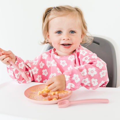 Girl sitting in high chair wearing the Carnation Flower Cutie Bib.