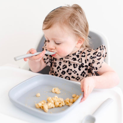 Toddler sitting in high chair eating with the Cutie Spoovel.