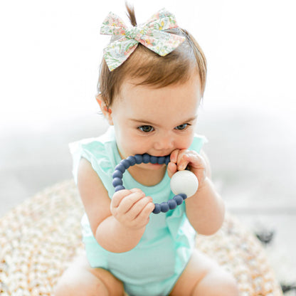 Baby girl teething on the Captain Cutie Teether.