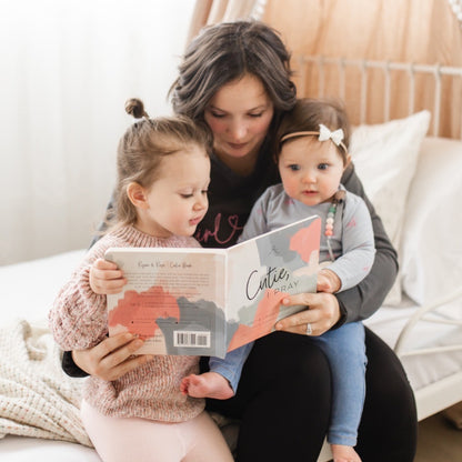 A mom reading Cutie, I Pray to her daughters.