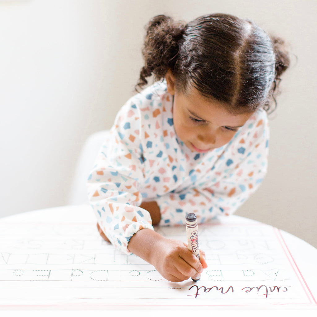 Girl drawing on Cutie Mat wearing the Terazzo Cutie Bib.