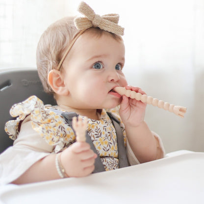 Baby sitting in high chair using Cutie Tensils.