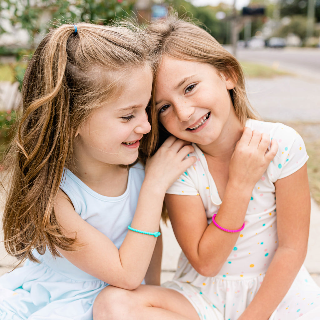 Two girls wearing a Cutie Bracelet.