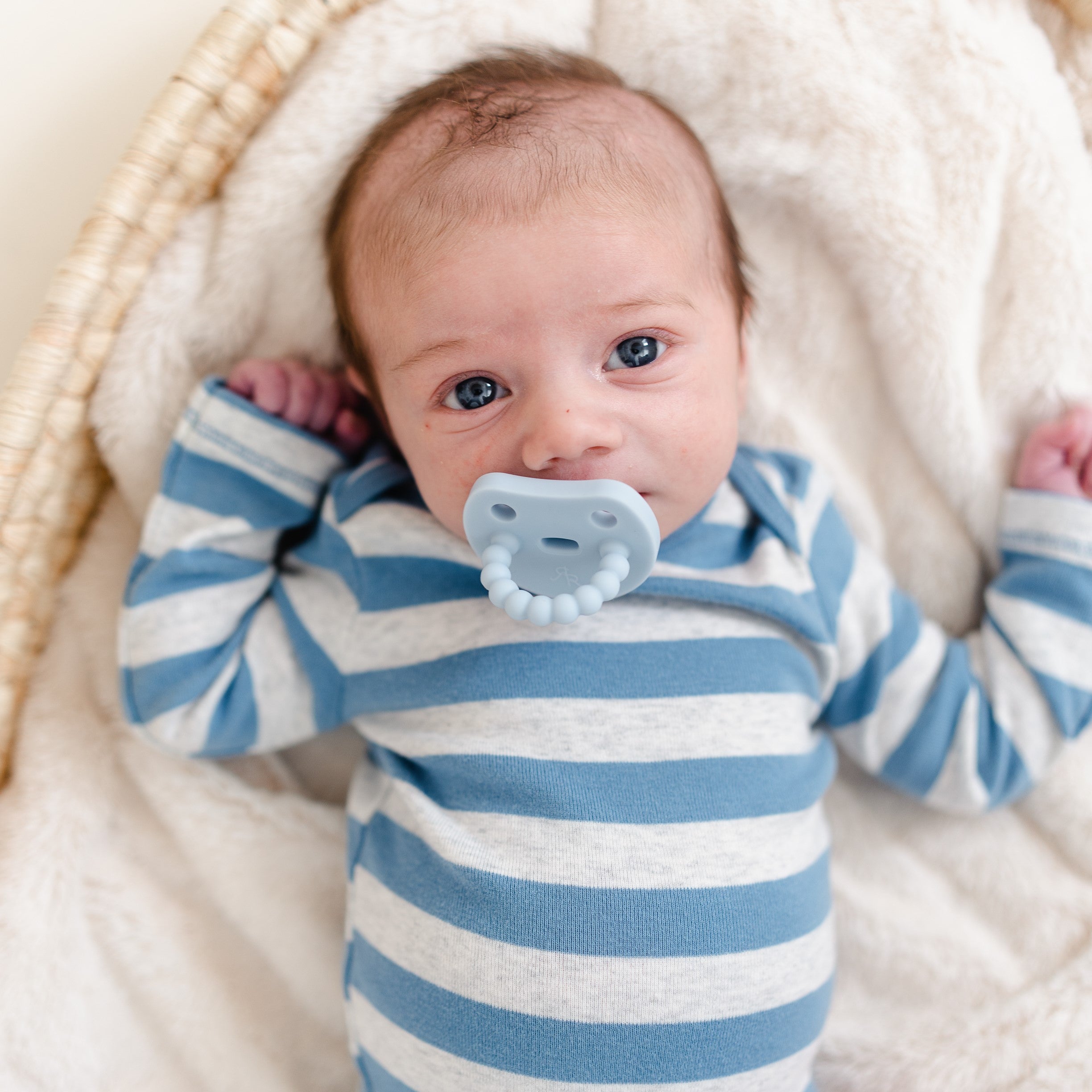 Baby sucking on a Cutie PAT Smile pacifier.