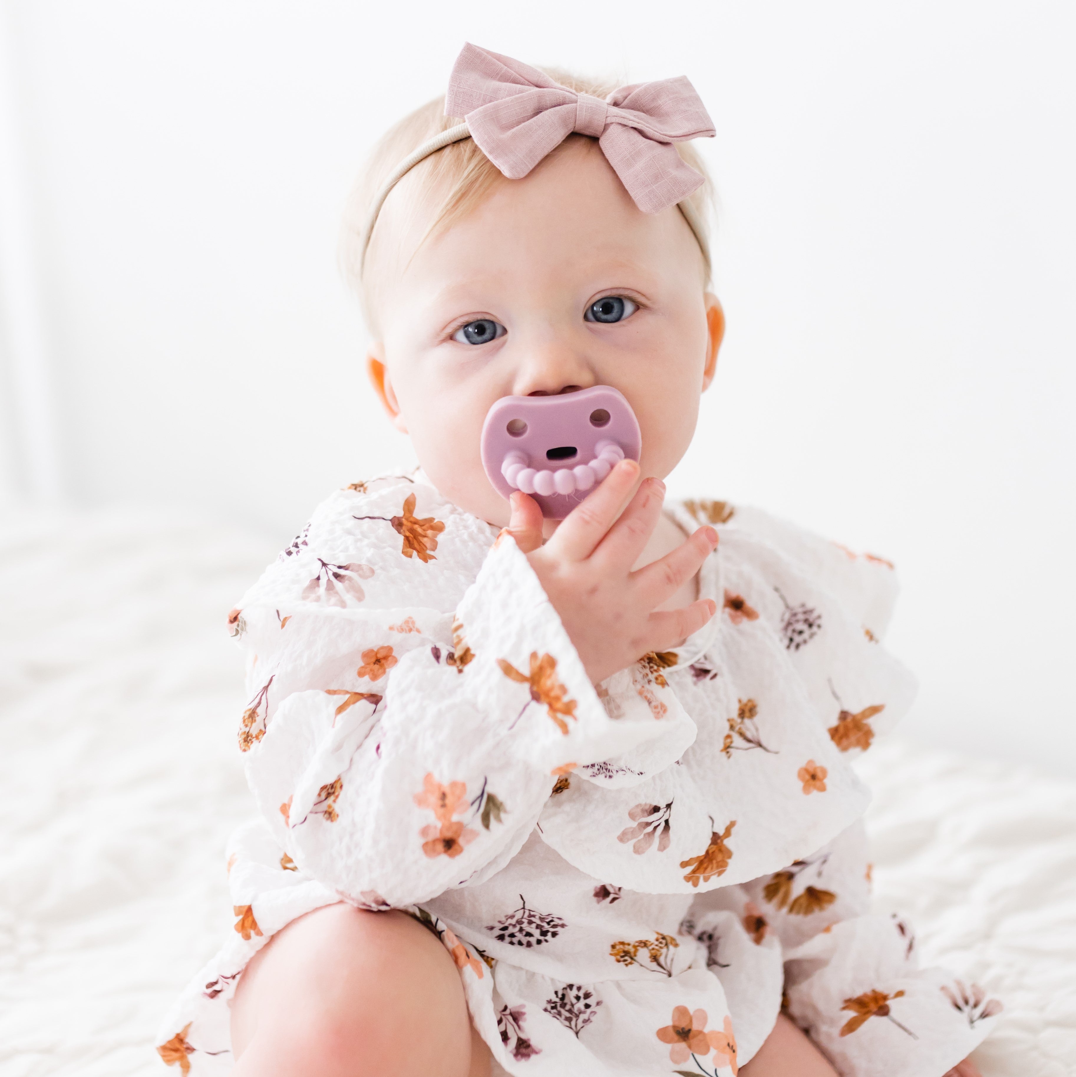 Baby sucking on a Cutie PAT Smile pacifier.