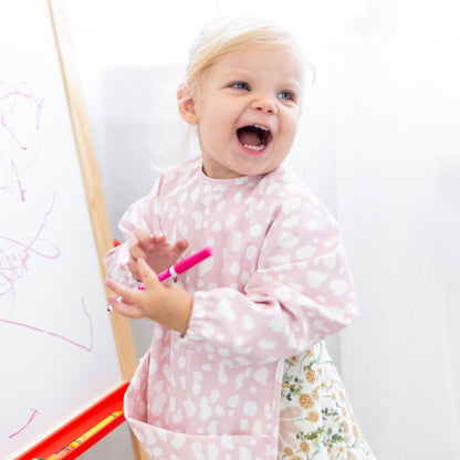 Girl drawing wearing the Blush Cheetah Cutie Bib.