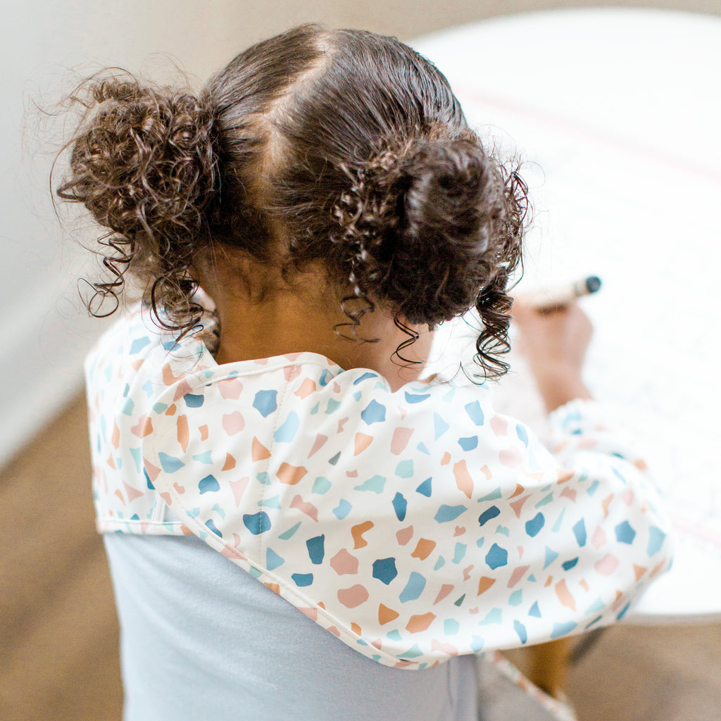 Girl drawing wearing the Terazzo Cutie Bib.