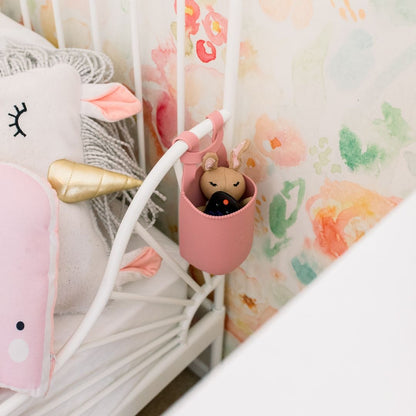 Cutie Holder attached to a bed frame holding a stuffed animal and remote.