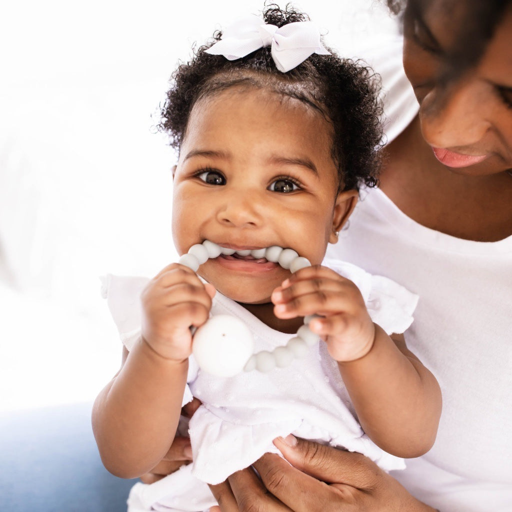 Baby girl teething on the Slate Cutie Teether.