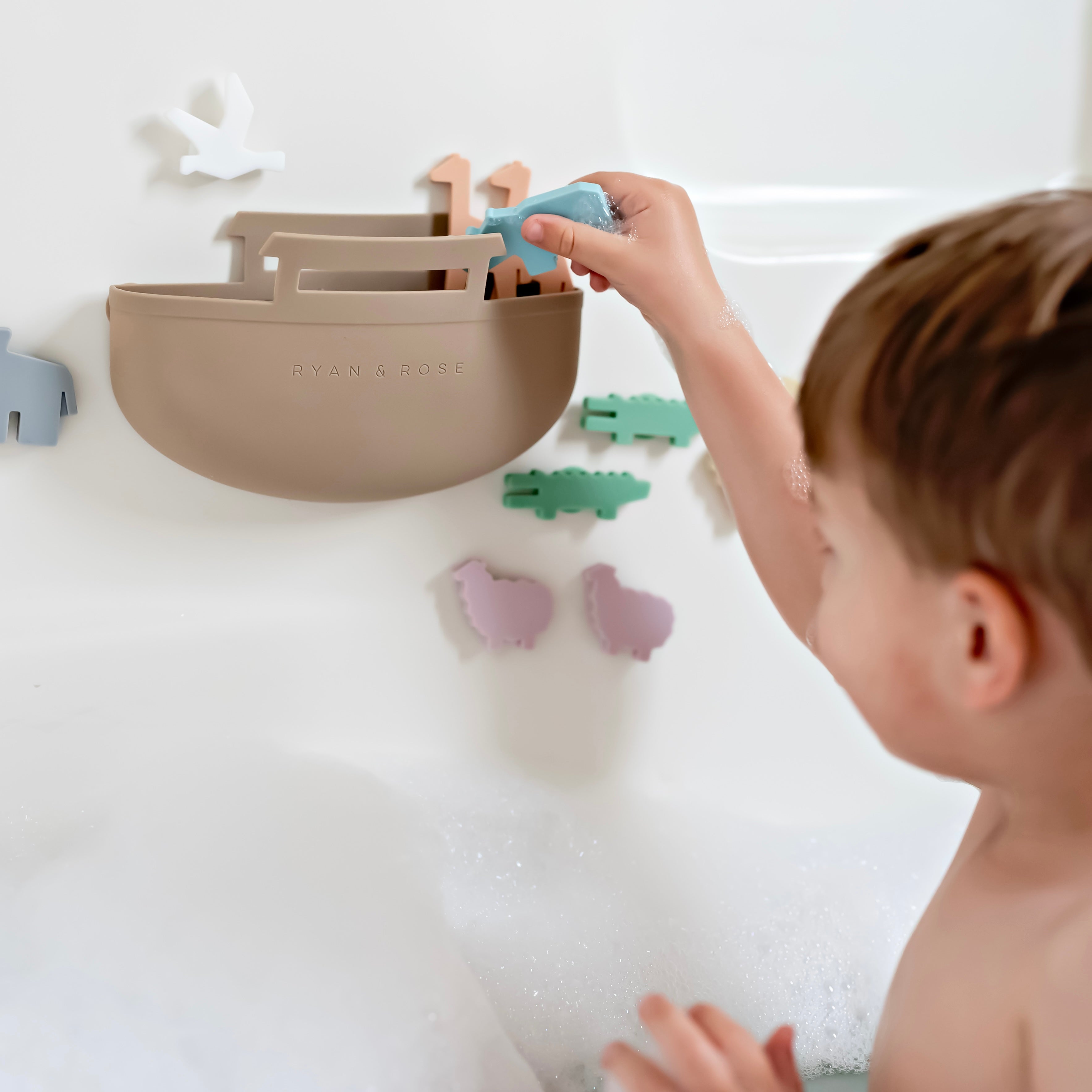 Toddler in bath tub playing with Noah’s Ark toy