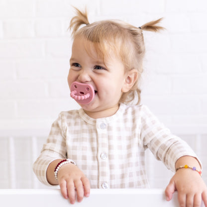 Baby sucking on a Cutie PAT Smile pacifier.