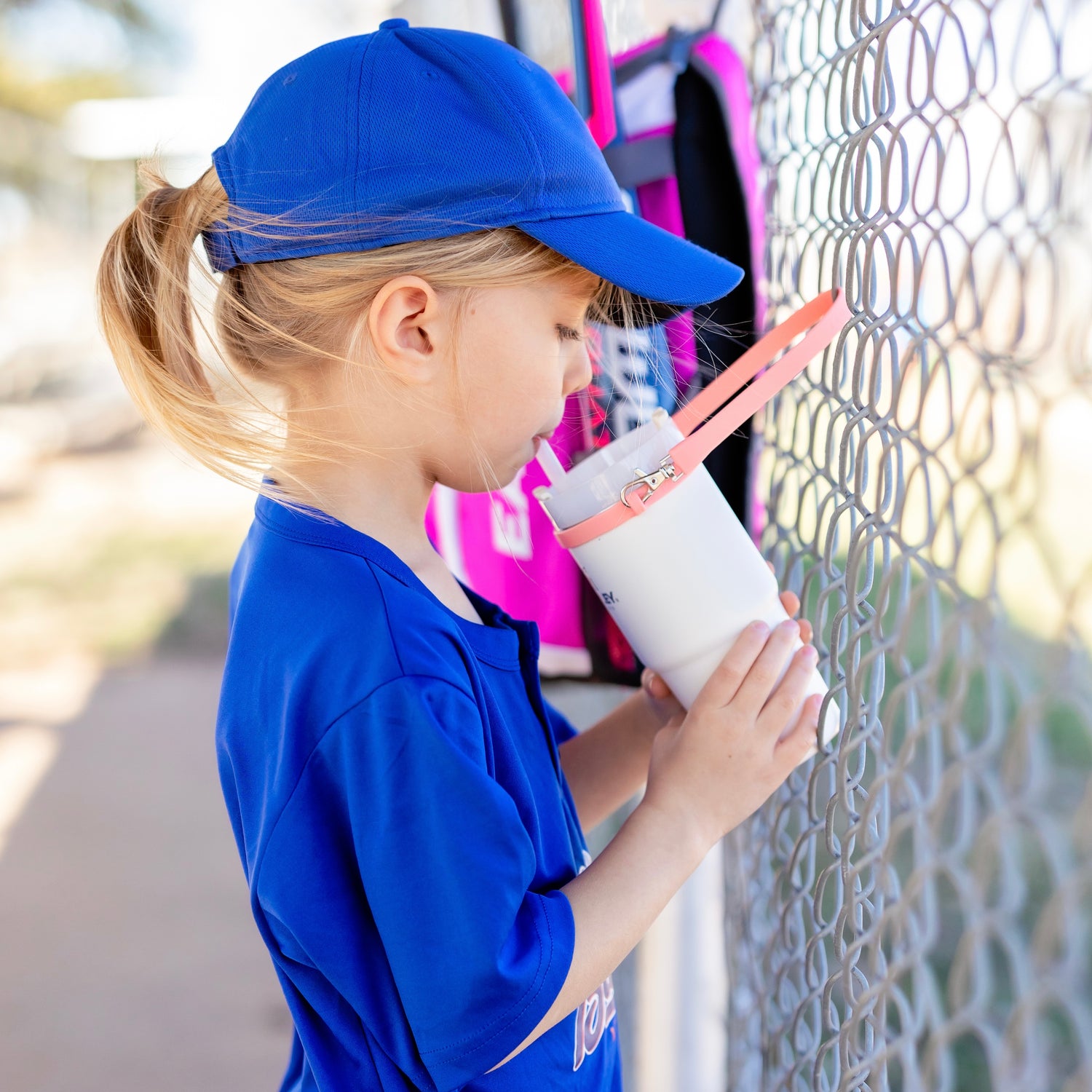 Girl drinking water on the baseball field.