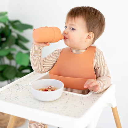 Baby in a high chair eating with Ryan &amp; Rose accessories