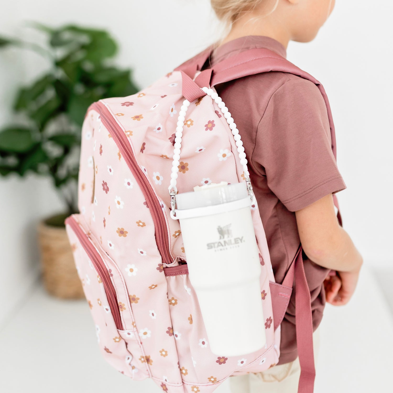 Girl wearing a backpack with a White Cutie Handle attached holding a waterbottle.