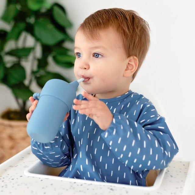 Baby boy drinking out of a Cutie Cup wearing the Cutie Bib.