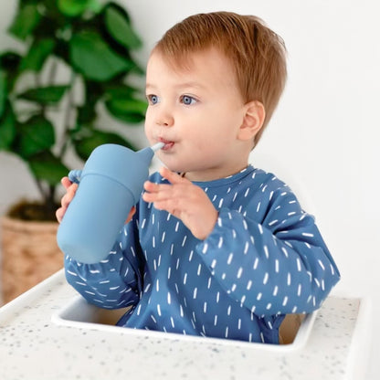 Baby boy drinking out of a Cutie Cup wearing the Cutie Bib.