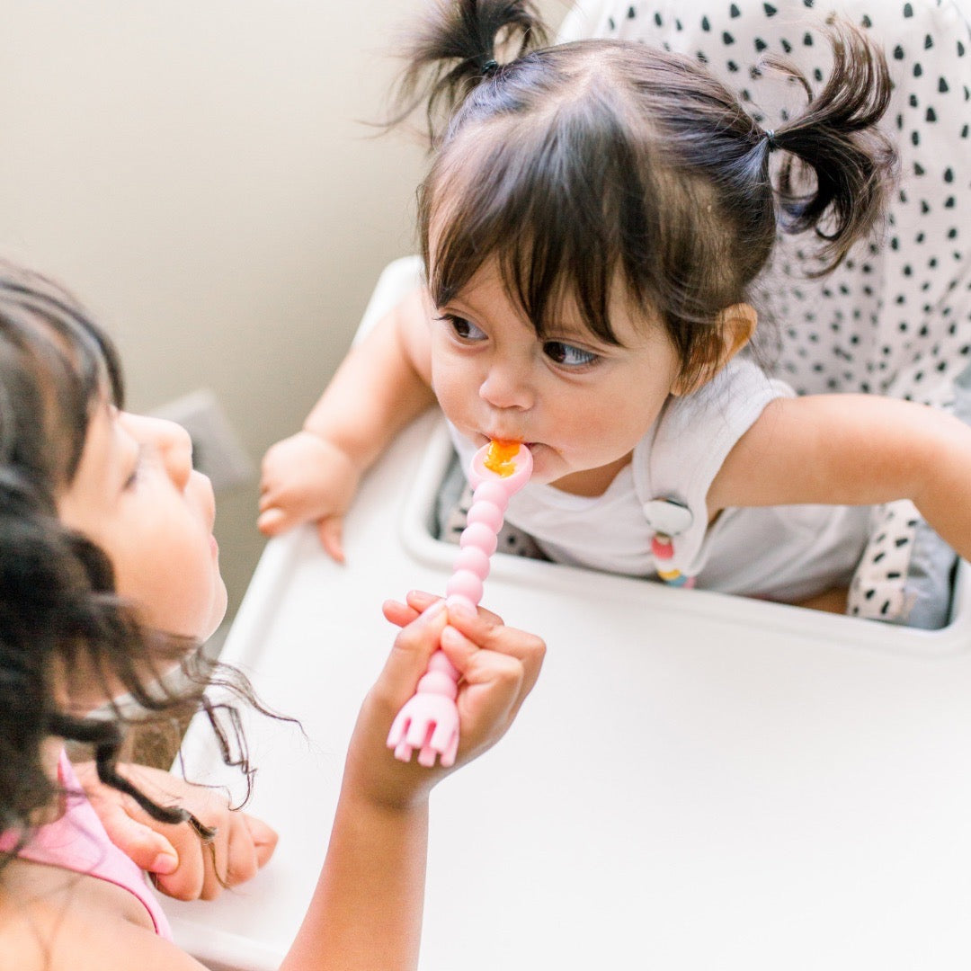 Big sister feeding little sister using Cutie Tensils.