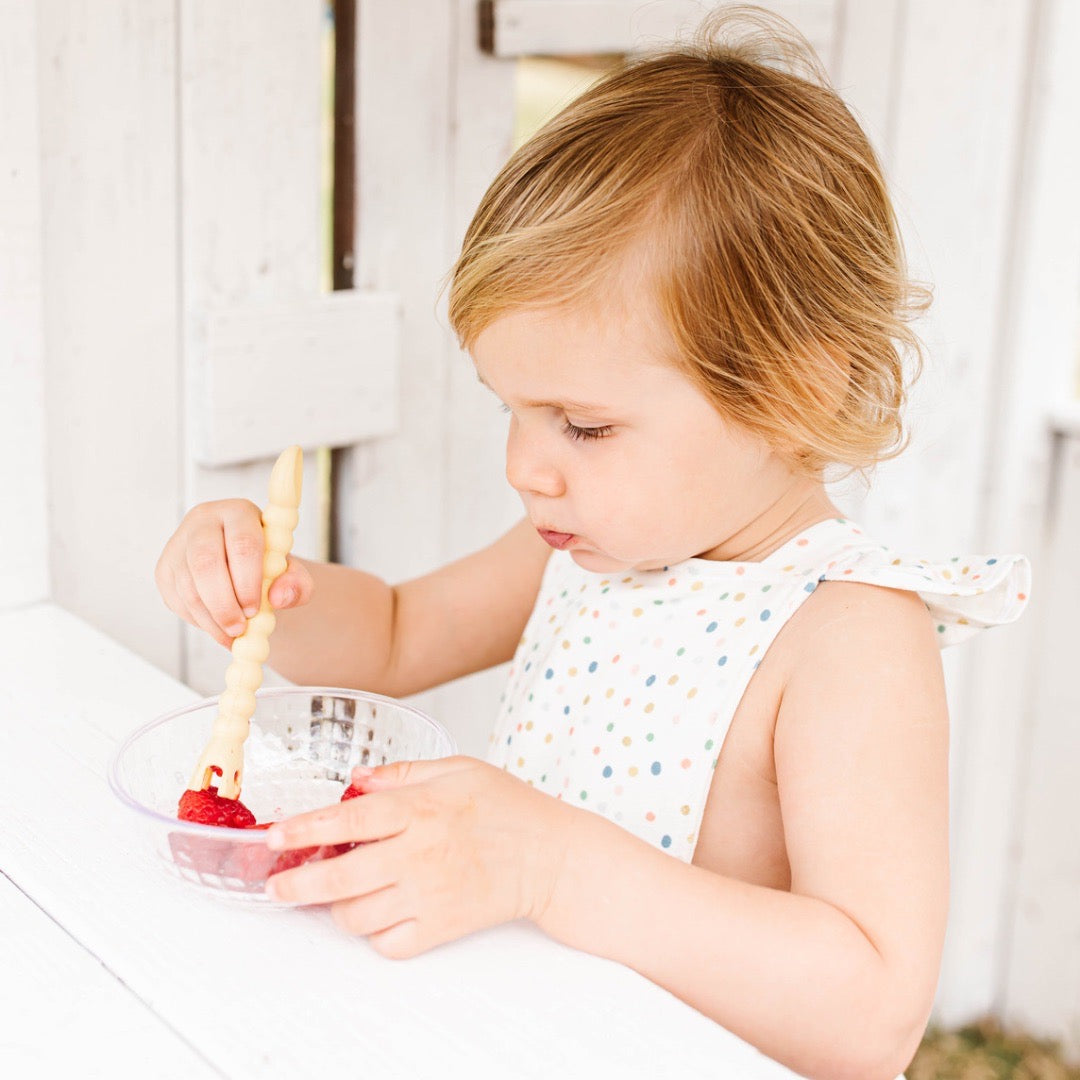 Girl eating raspberries using Cutie Tensils.