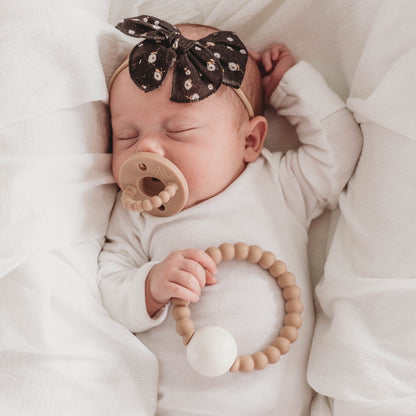 Baby girl holding the Dune Cutie Teether.