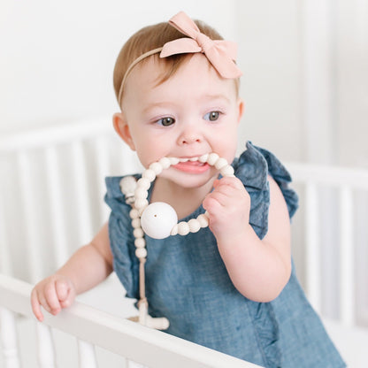 Baby girl teething on the Ivory Cutie Teether.