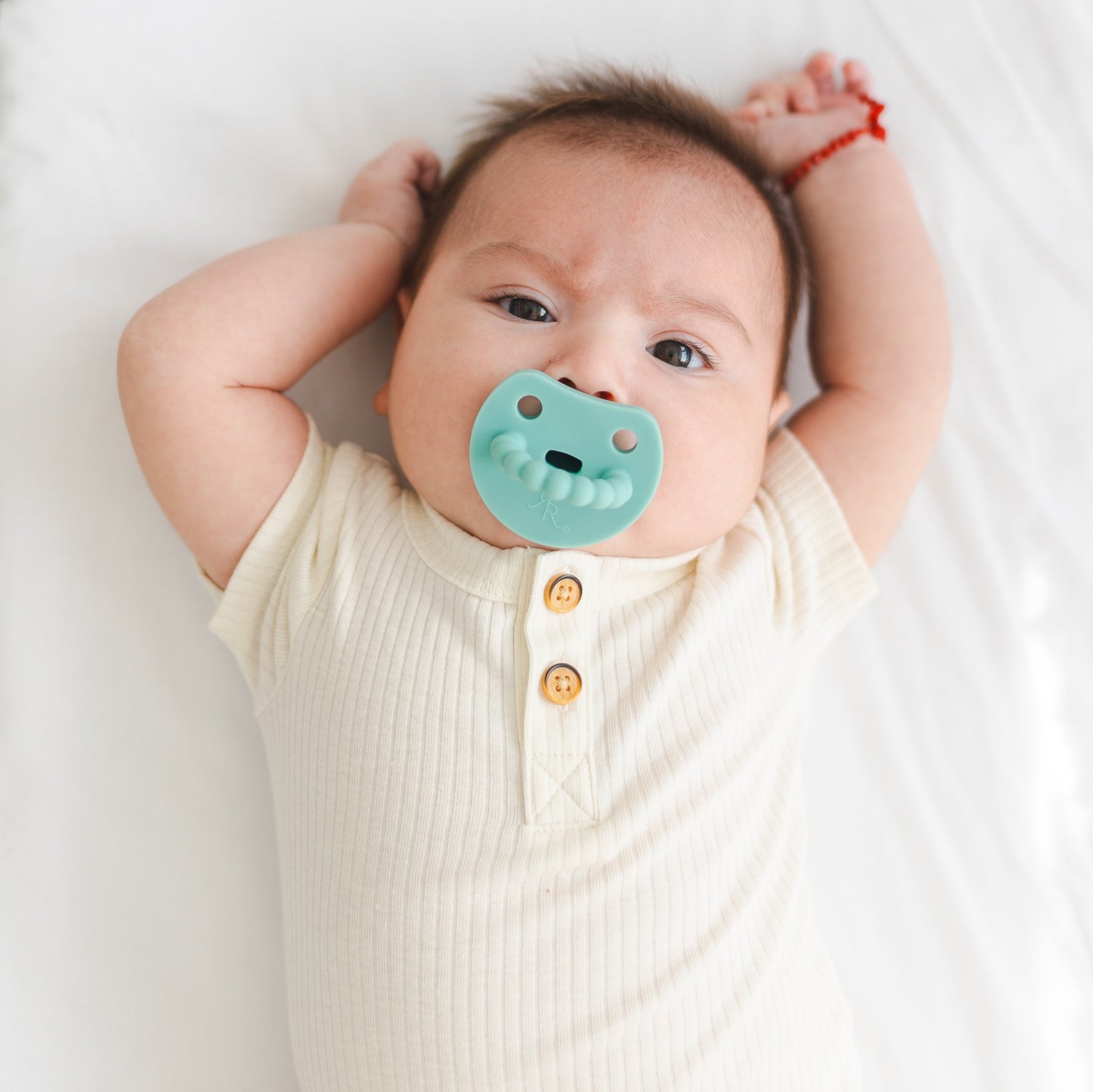 Baby sucking on a Cutie PAT Smile pacifier.