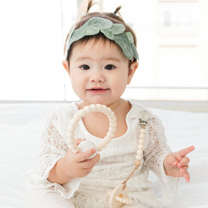 Baby girl holding the Ivory Cutie Teether.