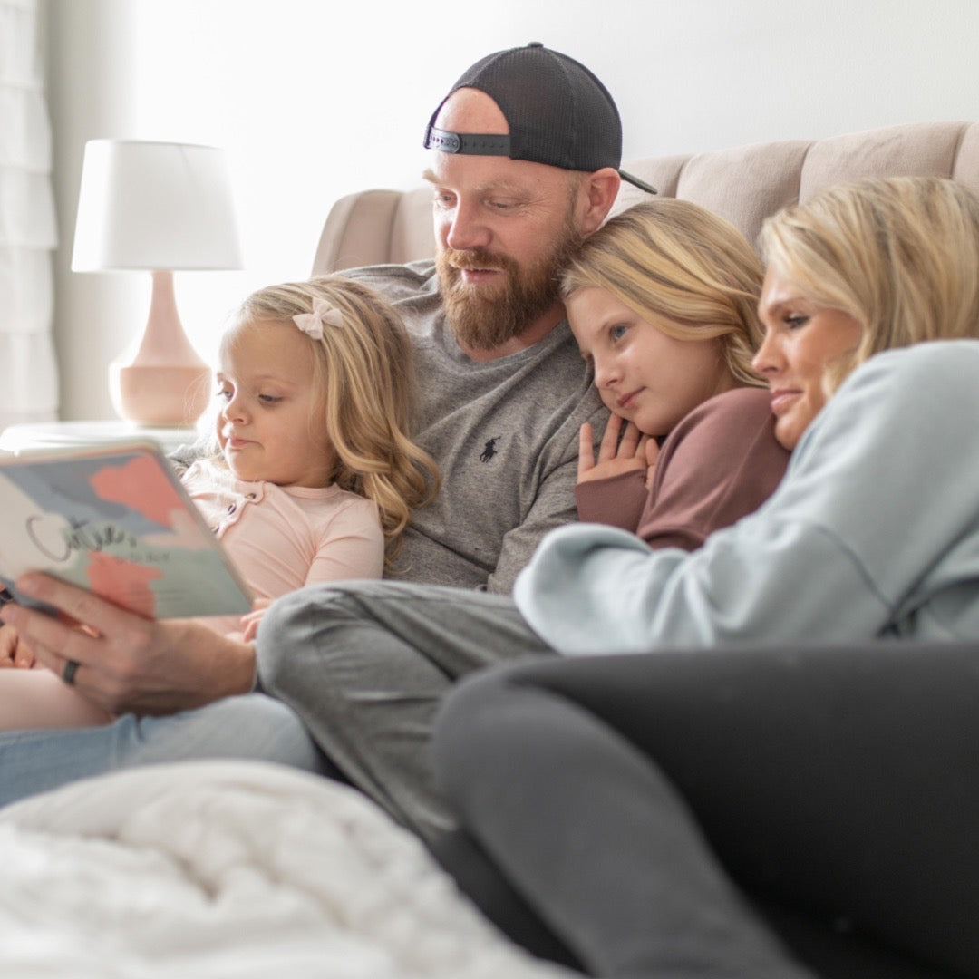 Lindsey and Bret, reading Cutie, I Pray to their daughters Ryan and Charley.