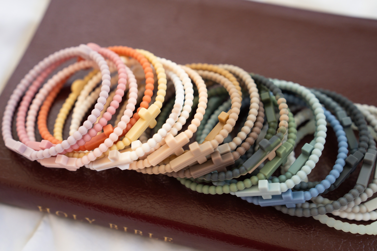 Set of colorful beaded Jesus bracelets on a brown Bible cover