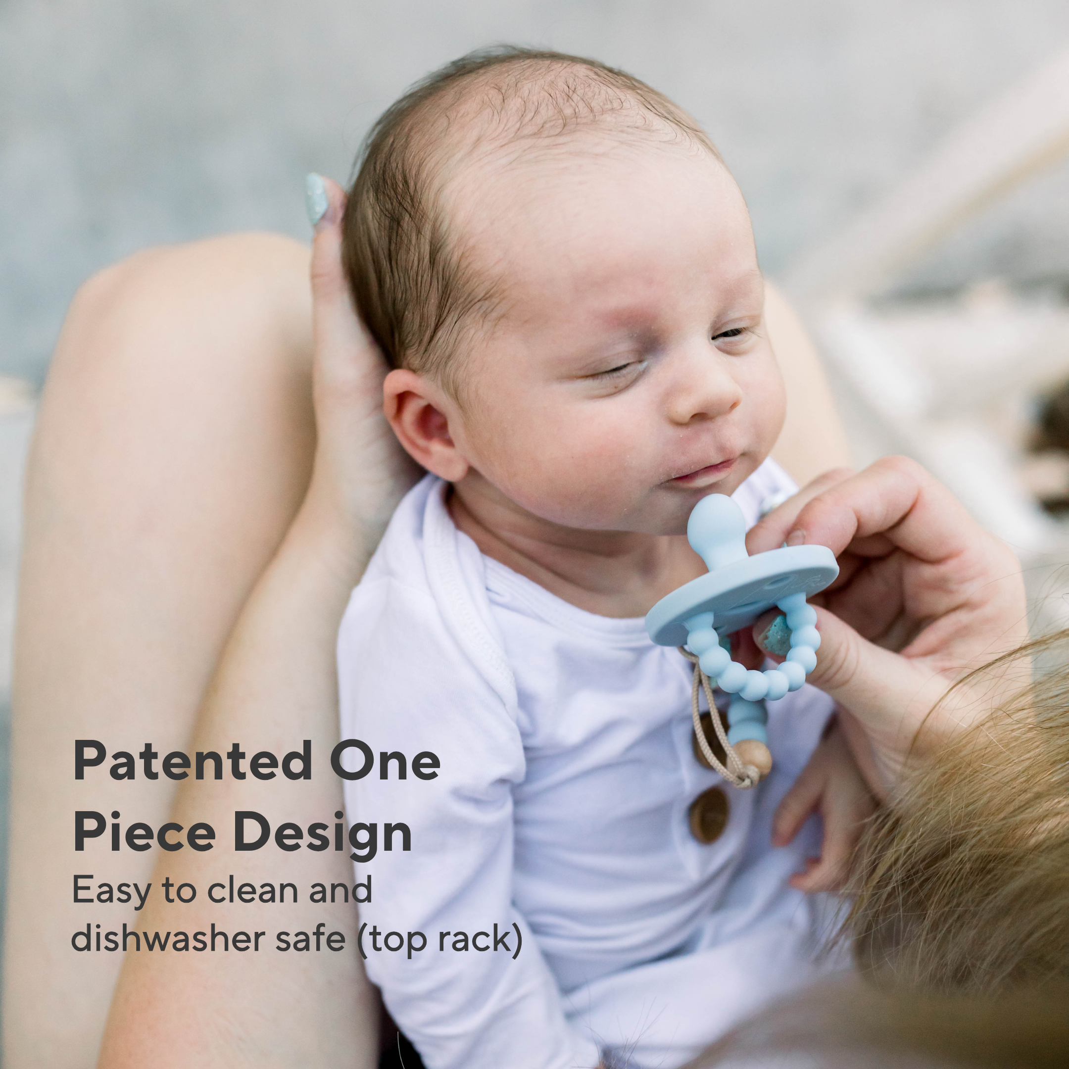 Baby holding a blue teething ring with text about its design and features.