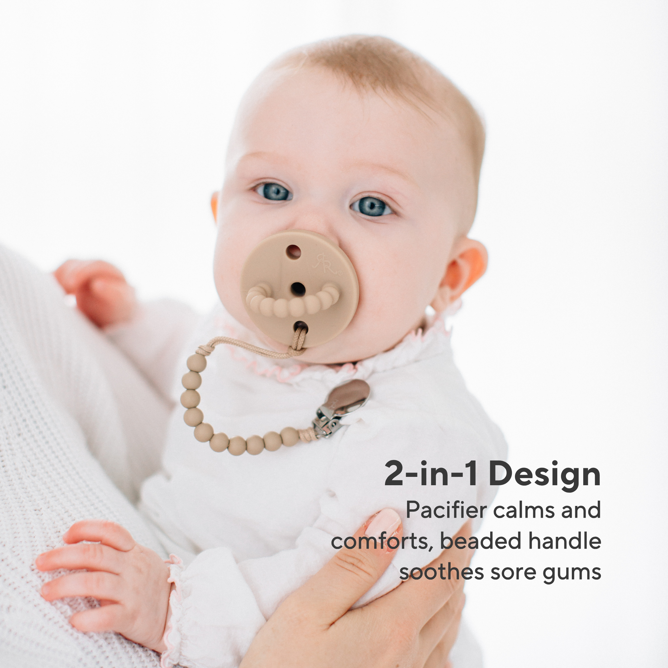 Baby wearing a 2-in-1 pacifier with a beaded handle, held by an adult.