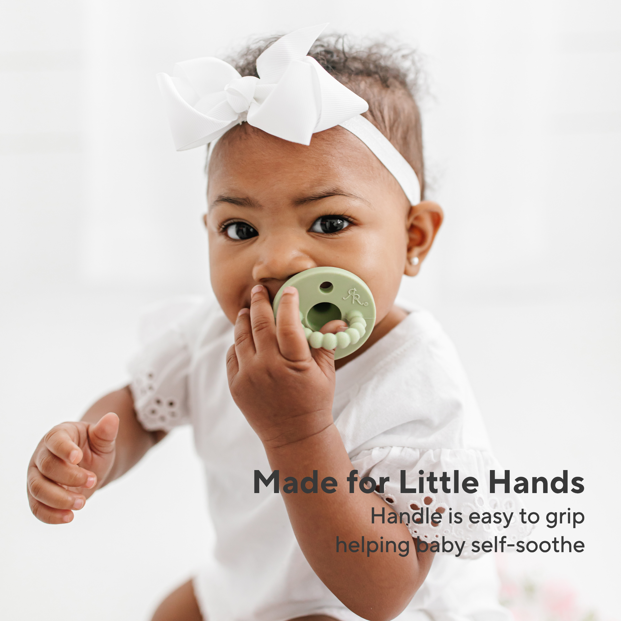 Baby holding a green teething ring with text &