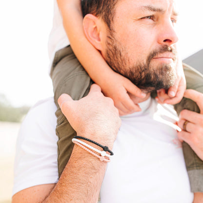 A dad carrying a child on his shoulders wearing the Core Cutie Bracelets.