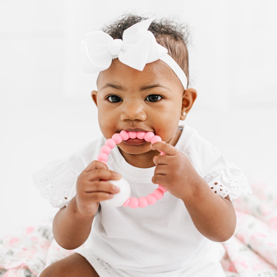 Baby girl teething on the Taffy Cutie Teether.