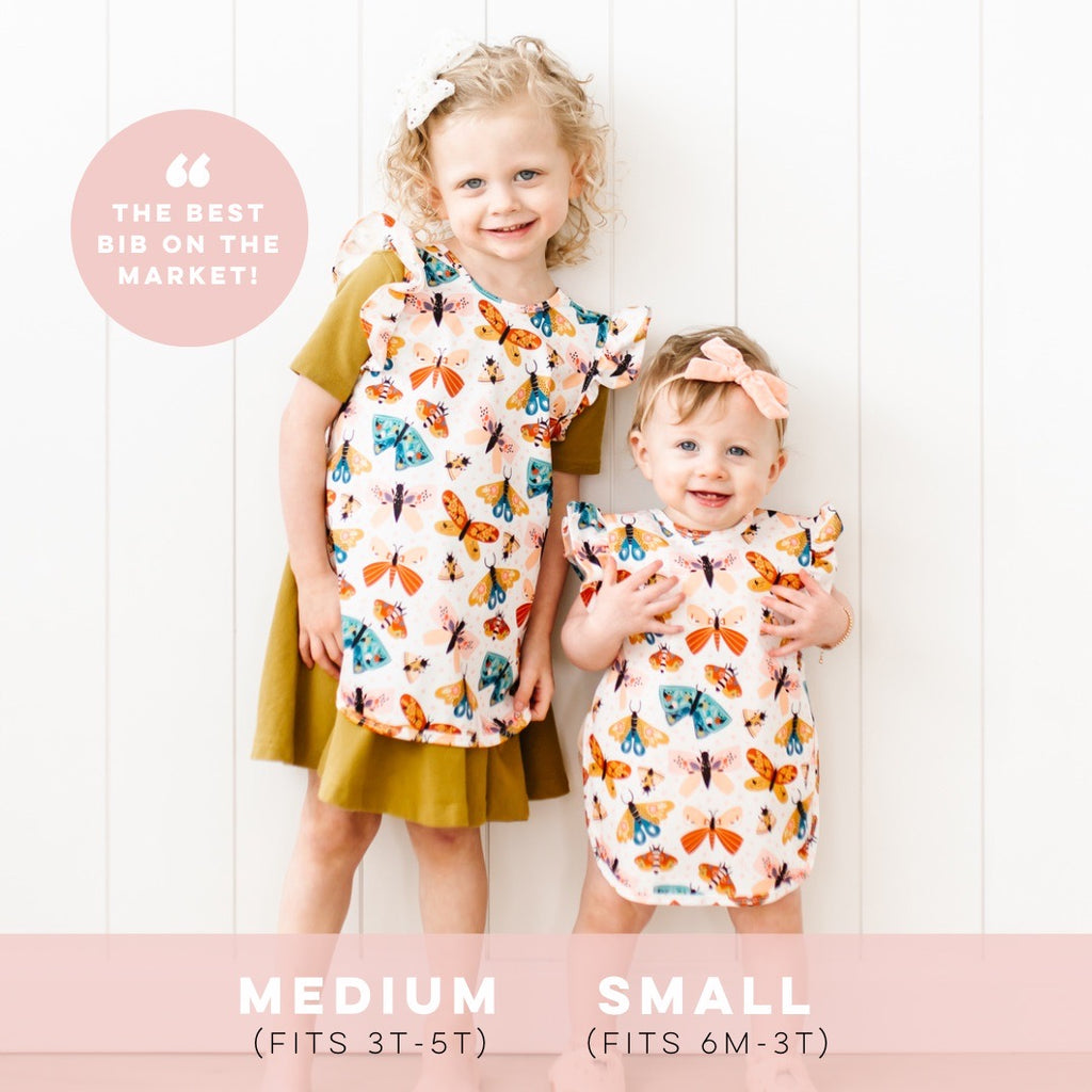 Sisters wearing Cutie Baprons showing size difference. Medium (left) fits 3T-5T and Small (right) fits 6M-3T.