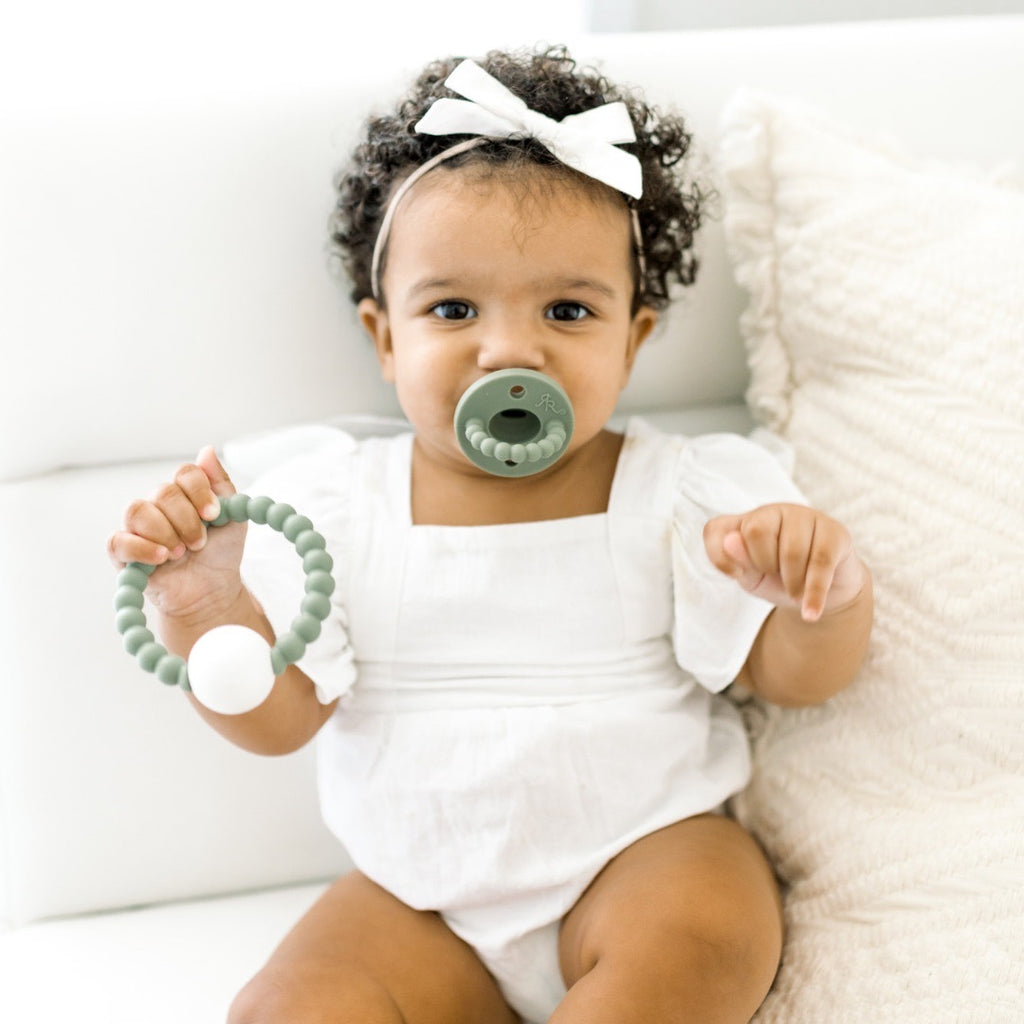 Baby girl holding the Ivy Cutie Teether.