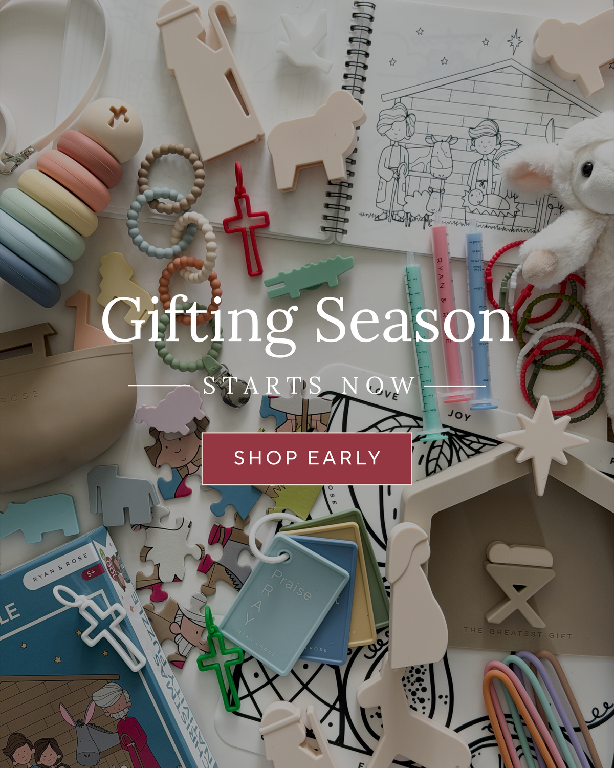 A styled flat-lay of assorted gift items on a light neutral background, including pastel wooden animal cutouts, bead necklaces, colorful hair ties, a plush toy, drawing books, and small decorative accessories. Large overlaid text reads 'Gifting Season Starts Now' with a 'Shop Early' button.
