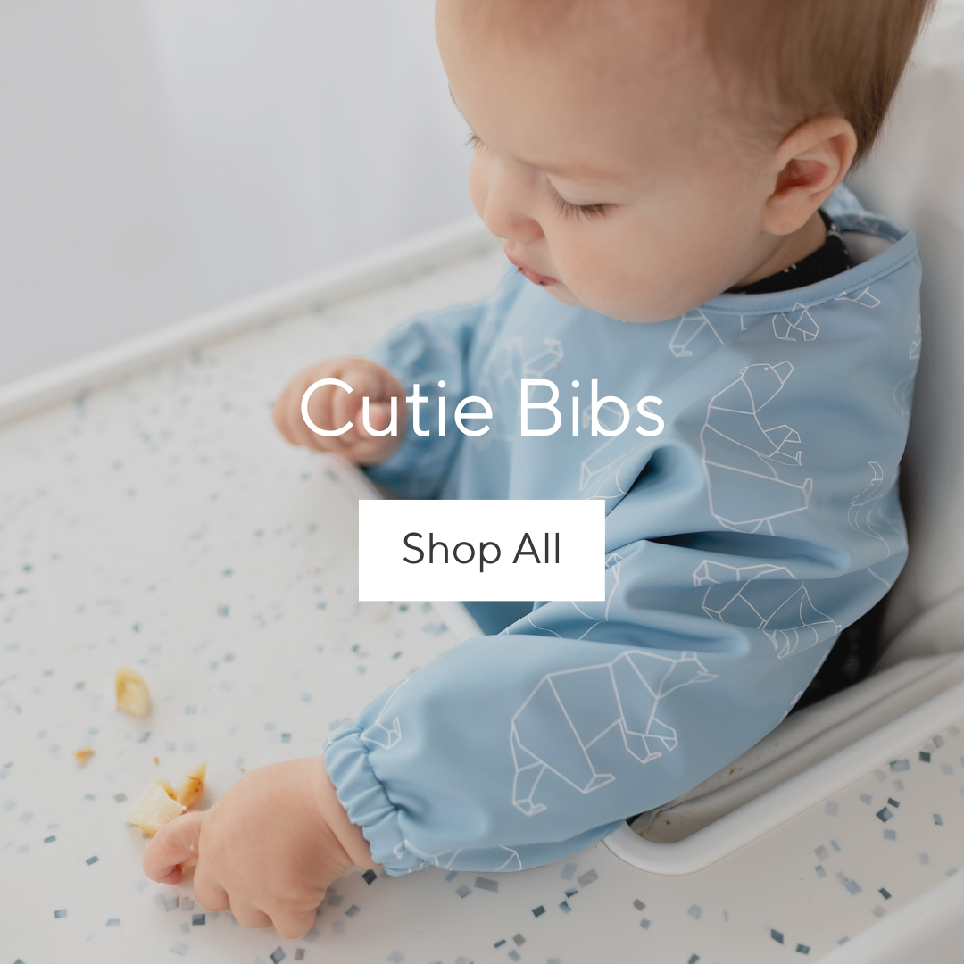 Baby eating in a high chair wearing a Cutie Bib.