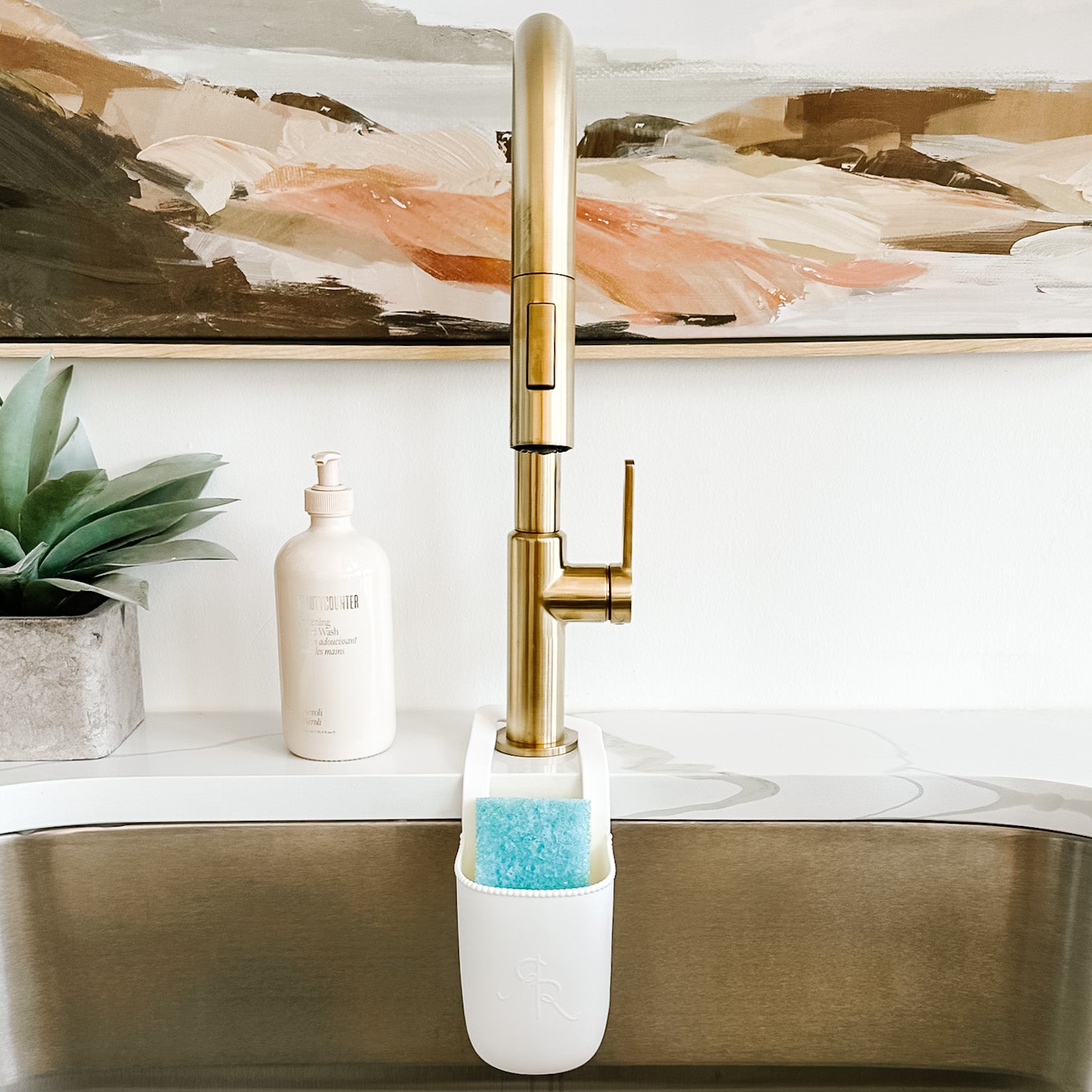 Cutie Holder hanging on a kitchen sink faucet holding a sponge.