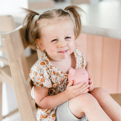 Toddler sitting in chair drinking out of cutie cup