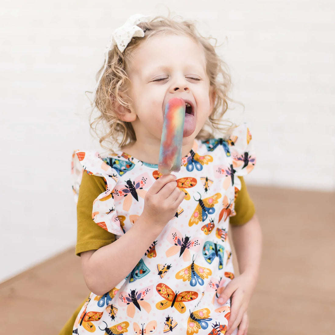 Child eating a popsicle wearing a cutie bapron