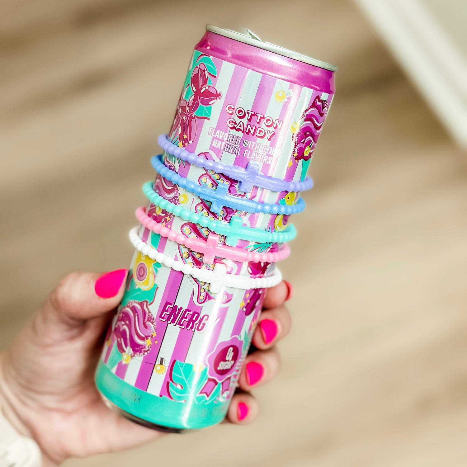 Hand holding a stack of colorful cotton candy-themed cups with hair ties.