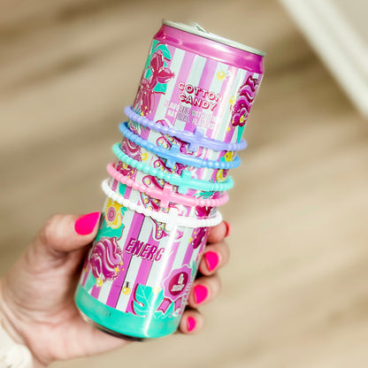 Hand holding a stack of colorful cotton candy-themed cups with hair ties.