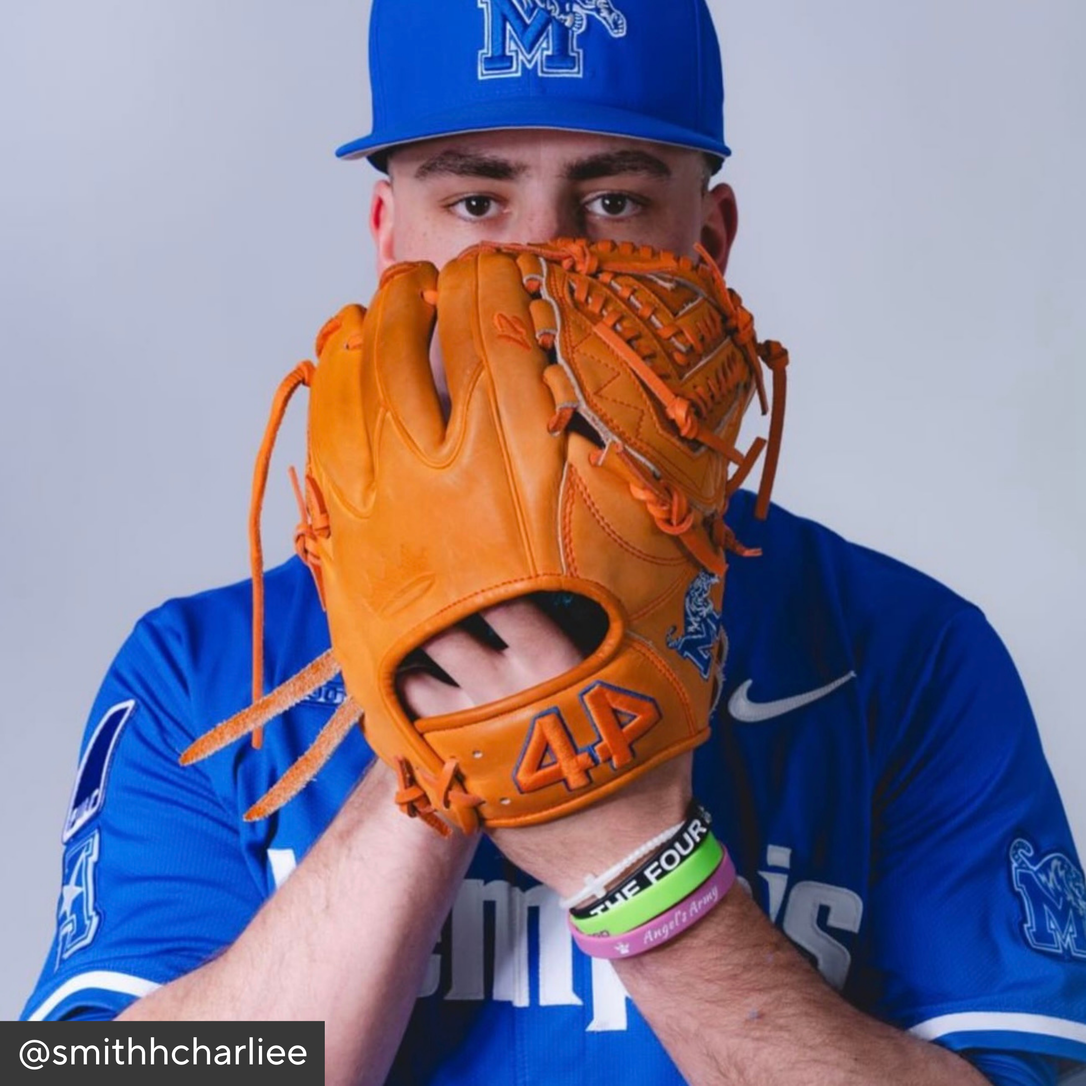 Person wearing a blue baseball uniform and orange glove with &