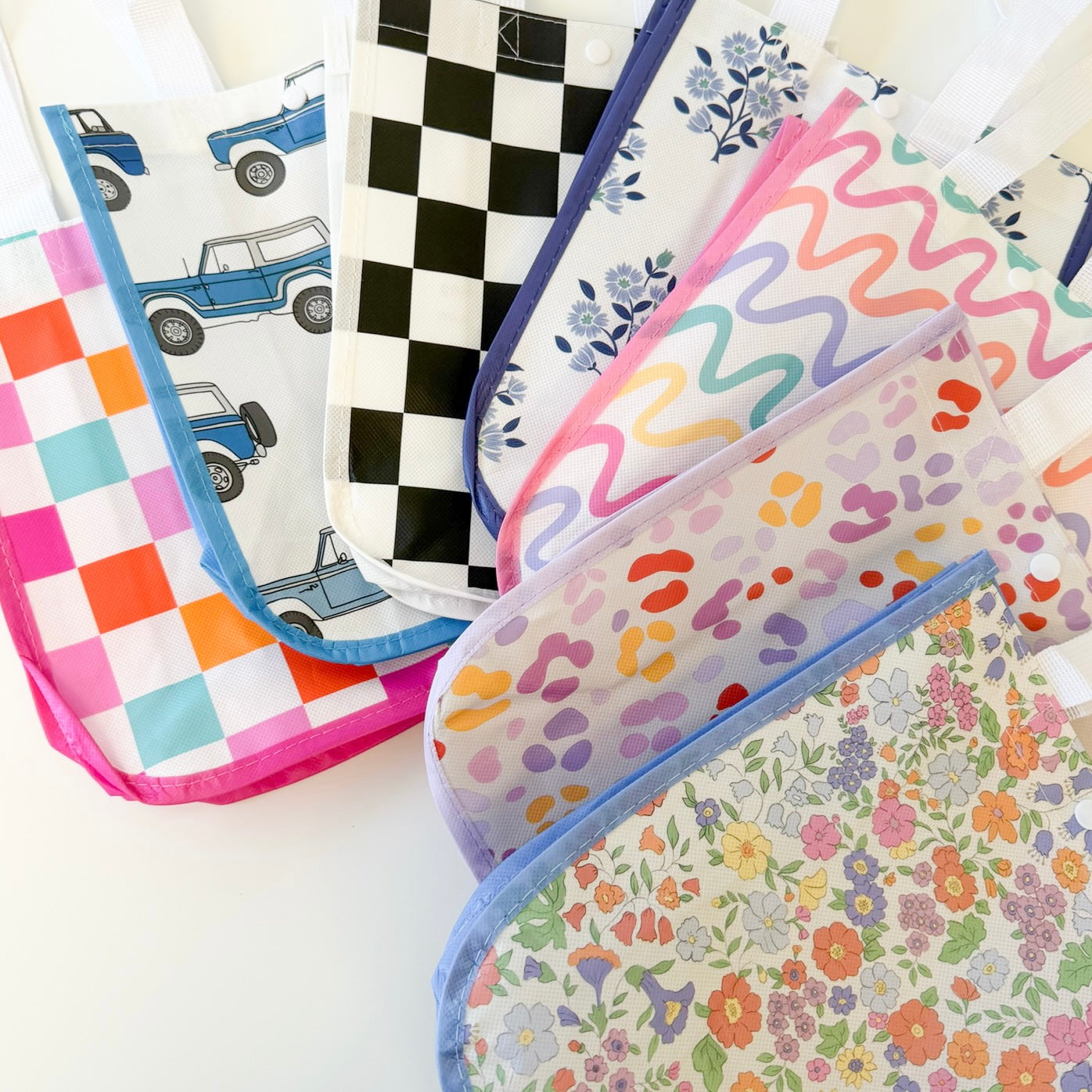 A set of colorful reusable tote bags with various printed patterns, including checkered, wavy, leopard print, and floral designs, arranged on a white background.
