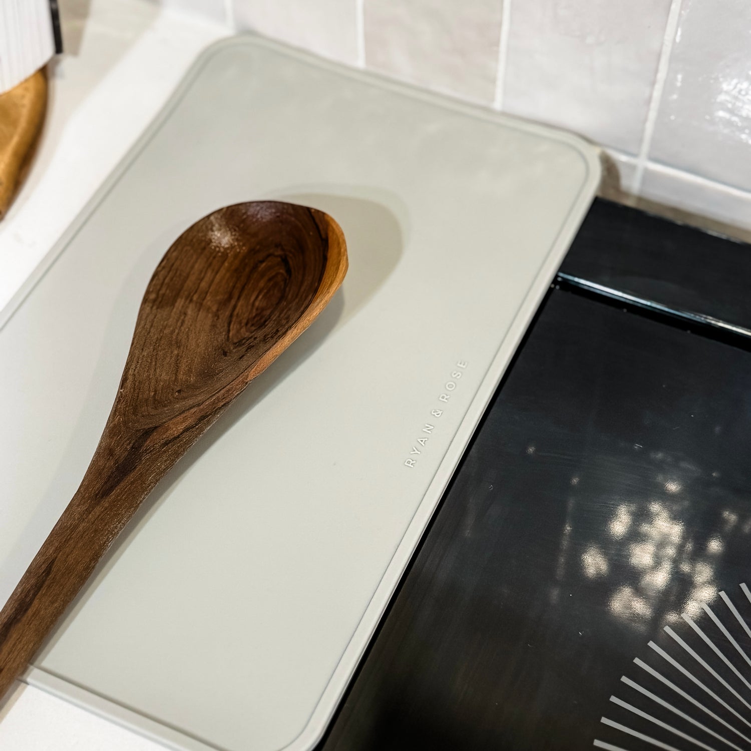 Wooden spoon on a white trivet with a black stovetop in the background