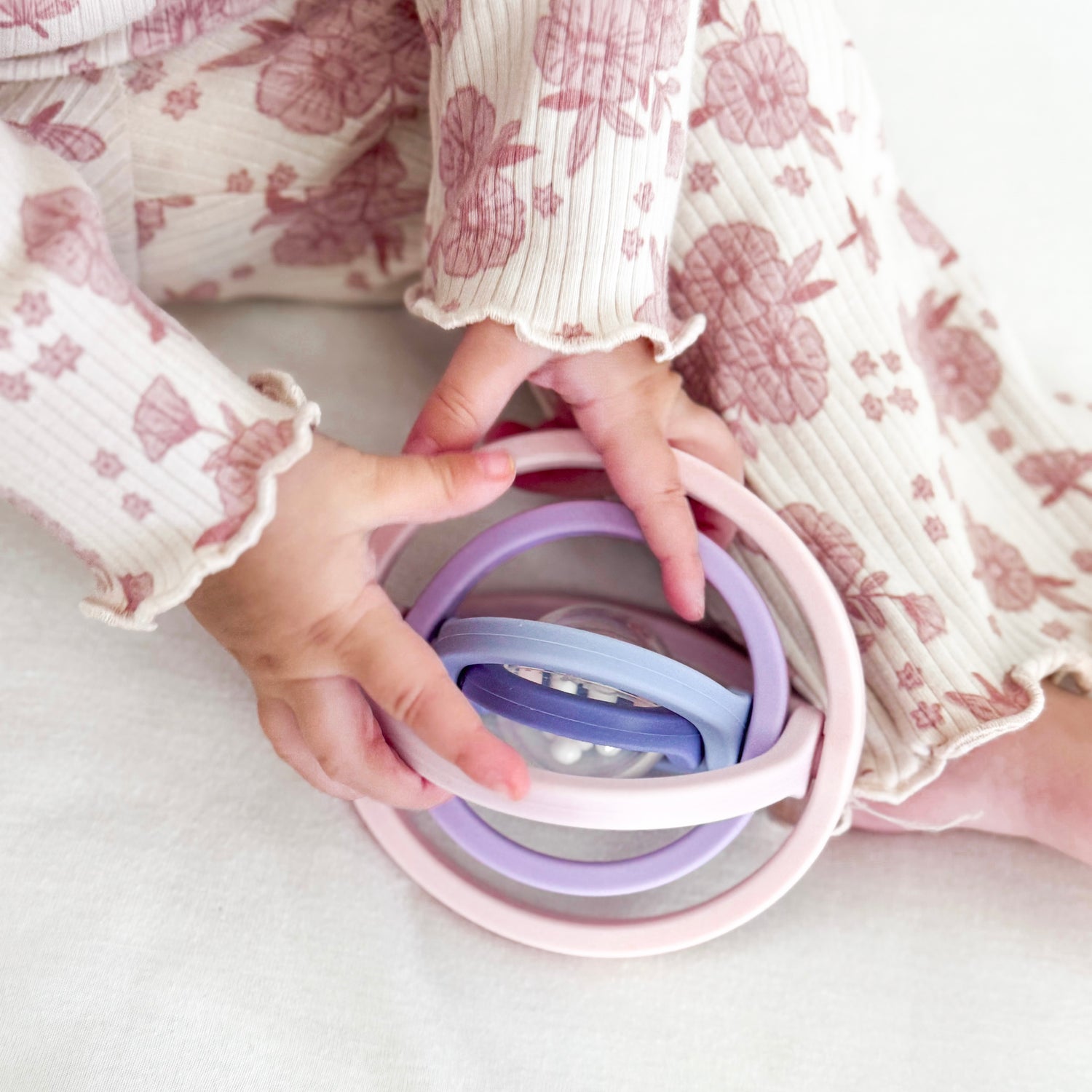 Pastel-colored silicone ring set held by a person wearing a floral dress.