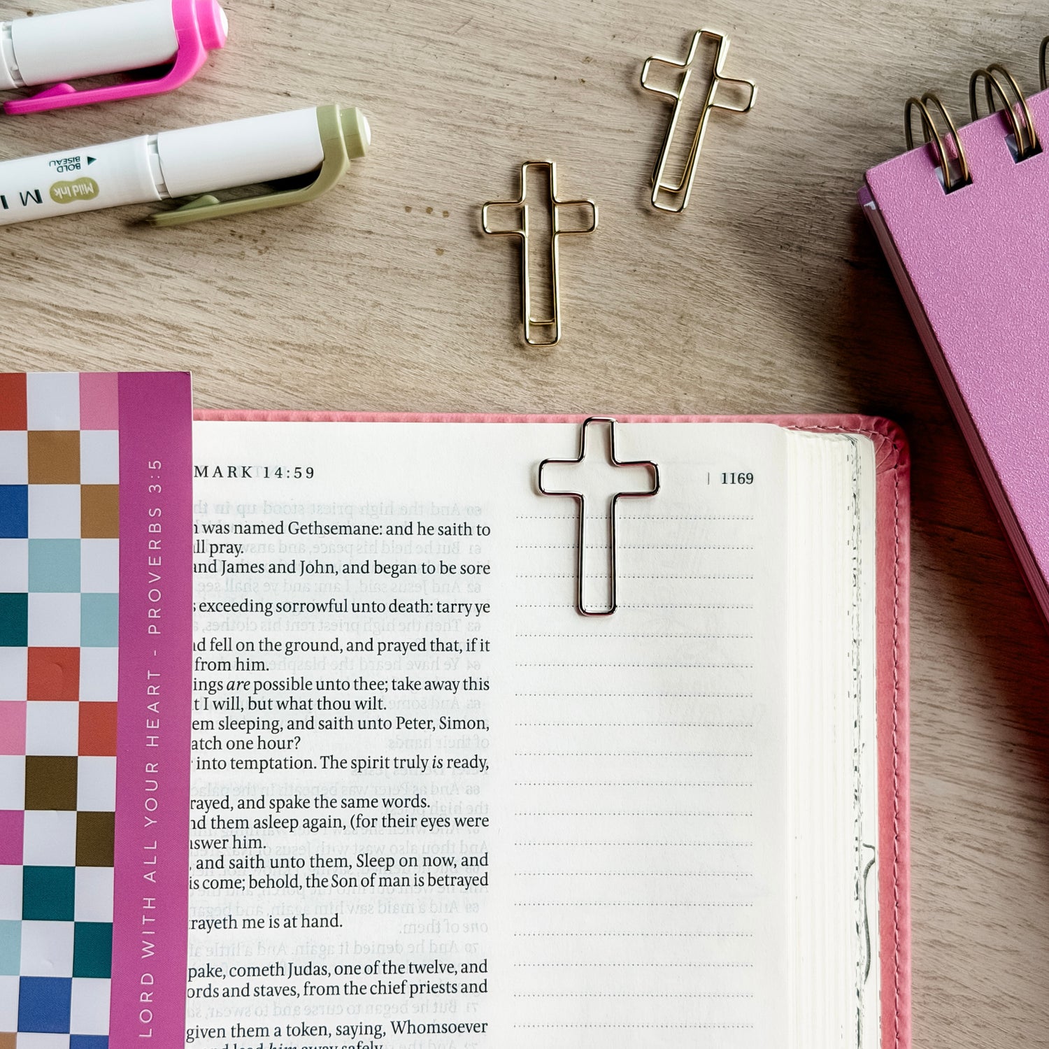 Open book with cross bookmarks on a wooden surface